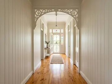 Restored Queenslander hallway with timber fretwork and a leadlight front door