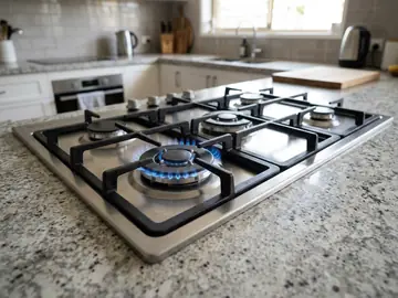 Gas cooktop installed in a stone benchtop, one burner lit